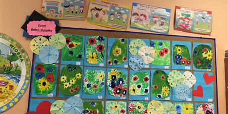 Powiększ grafikę: Tablica  z  przypietymi  pracami  plastycznymi  dzieci. Na  obrazkach przedstawione  są  kwiaty  na  zielonym  tle.