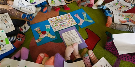 Powiększ grafikę: Dzieci z grupy 2 " Foczki" pozują w kolorowych skarpetkach z laurkami.