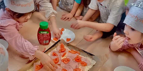 Powiększ grafikę: Timi wraz z dziećmi z  zaangażowaniem przygotowuje pizzę