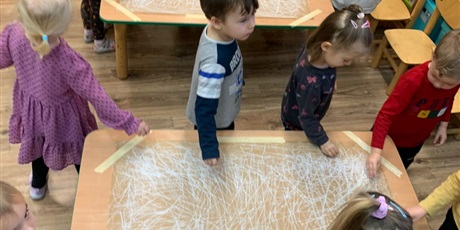 Powiększ grafikę: Dzieci kreślą rytmicznie jedną ręką kreski tworząc tło.
