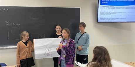Powiększ grafikę: Grupa  uczniów  przy  tablicy  prezentuje  wykonane  zadanie.