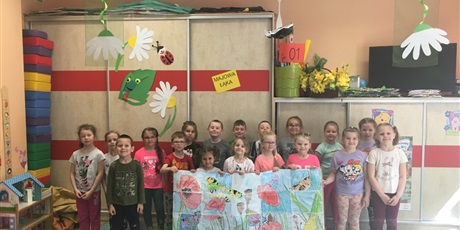 Powiększ grafikę: Grupa  przedszkolaków  stoi  na  tle  szafy  z  napisem  "Majowa  łąka". dzieci  w  pierwszym  rzędzie  trzymają  pracę  plastyczną  z  rysunkami  kwiatów  i  owadów.