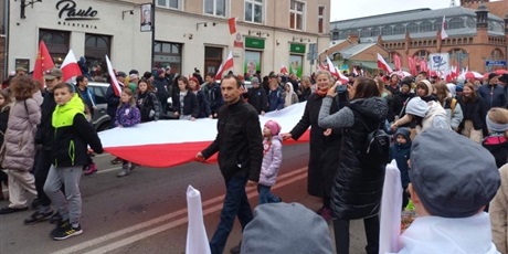 Powiększ grafikę: Grupa  dzieci  i  dorosłych  niesie  flagę  Polski  podczas  Parady  Niepodległości.