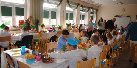 Powiększ grafikę: dzieci  siedzą  przy  stolikach  w  trakcie  słodkiego  poczęstunku.