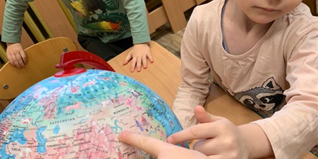 Powiększ grafikę: Dzieci na globusie pokazują gdzie znajdują się Chiny.