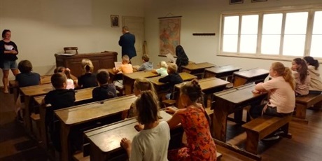 Powiększ grafikę: Dzieci  siedzą  w  ławkach  w  przedwojennej  sali  lekcyjnej, sala  muzealna.