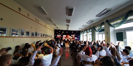 Powiększ grafikę: Aula  szkolna, na  widowni  siedzą  uczniowie  oglądający  występ.