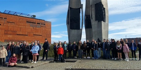 Powiększ grafikę: Grupa uczniów przed pomnikiem.